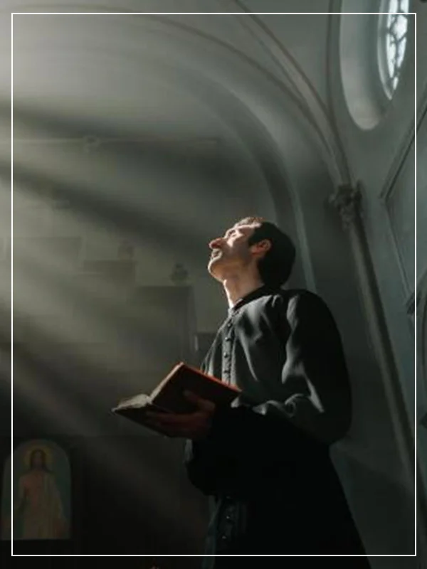 A man holding an open book in front of a window.